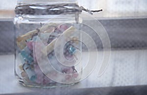 Glass jar with colored notes with blur and toning.