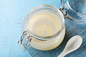 Glass jar with condensed milk or evaporated milk on blue rustic table. photo