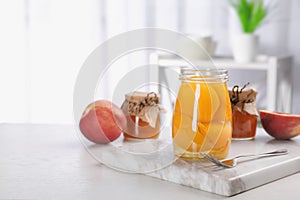 Glass jar with conserved peach halves on table