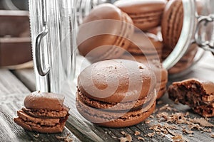 Glass jar and delicious chocolate macarons on table