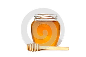 Glass jar with delicious fresh honey. There is a wooden ladle nearby. White isolated background.