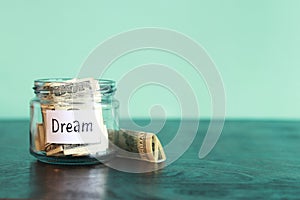 Glass jar with dollars on a wooden table. Piggy bank