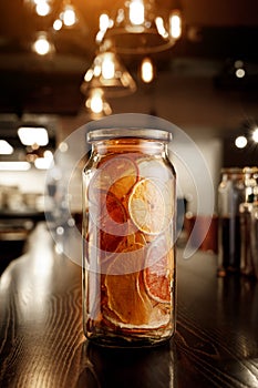 Glass jar with dried citruses on a wooden bar counter