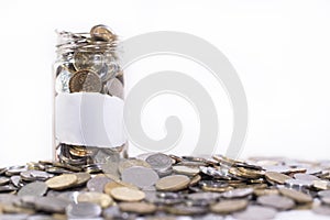 Glass jar filled with coins on a group of coins.