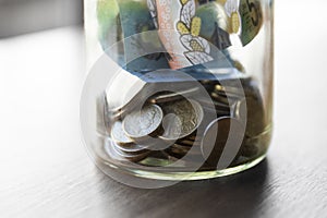 Glass Jar Filled with Coins and Money for Savings