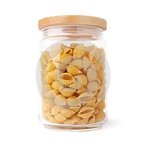 Glass jar filled with dry conchiglie pasta over isolated white background