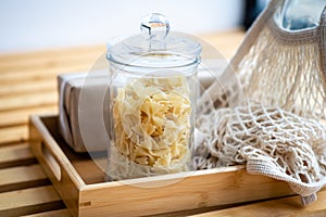 Glass jar filled with dry macarons. Yellow penne pasta
