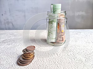 Glass Jar Filled With Euro Banknotes and Coins on Table. Concept of savings ranging from small money to large