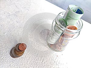 Glass Jar Filled With Euro Banknotes and Coins on Table. Concept of savings ranging from small money to large