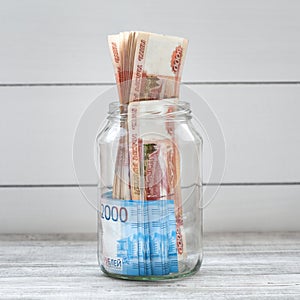 Glass jar filled with money on a light background