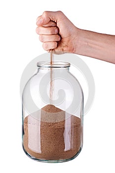 Glass jar with fist and sand on white background