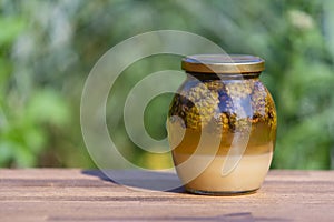 Glass jar of fresh honey with pine cones on a wooden table, closeup