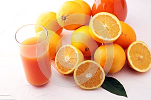 Glass jar of fresh orange juice with fresh fruits on white table