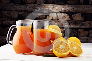 Glass jar of fresh orange juice with fresh fruits on white table