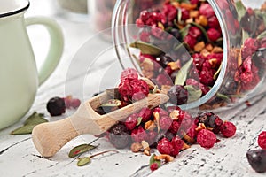 Glass jar of fruit tea with apples, orange, red and black currant berries close up on white kitchen table