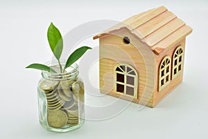 Glass jar full of coins and a miniature wooden house