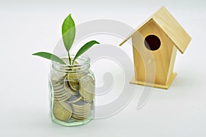 Glass jar full of coins and a miniature wooden house photo