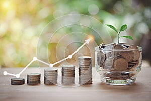 A glass jar with full coins and plant on top, money stacking for saving money concept, home, loan, step to keep money