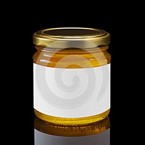 Glass jar full of honey with white label on black background