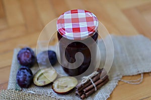 Glass jar full with plum jam on decorated desk