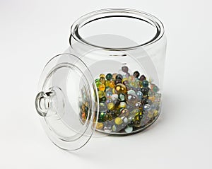 Glass jar half full of colorful glass marbles