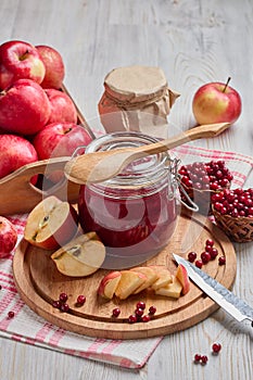 Glass jar of homemade jam from lingonberries and  red apples. Still life with fresh fruit and berries on light wooden table