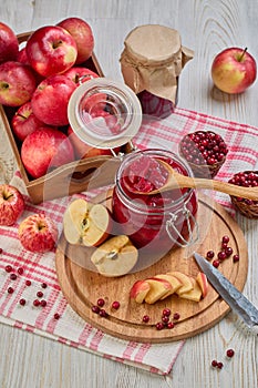 Glass jar of homemade jam from lingonberries and  red apples. Still life with fresh fruit and berries on light wooden table