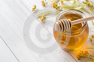 Glass jar of honey, Linden flowers on light background. Copy space