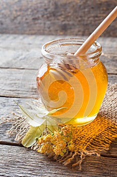 Glass jar of honey, Linden flowers on wooden background