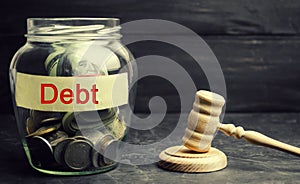 A glass jar and the inscription `debt ` and a wooden gavel. Payment of taxes and of debt to the state. Concept of financial crisis