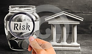 A glass jar and the inscription `risk` stands next to a state building. The concept of financial and economic risk. Unreliable inv