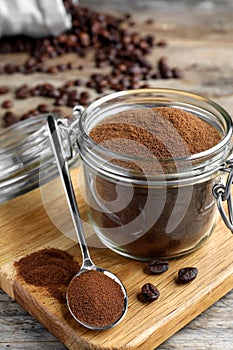 Glass jar of instant coffee and spoon on wooden table, closeup