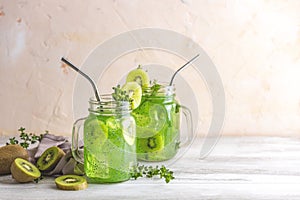 Glass jar of kiwi juice or smoothie. Kiwi Mojito cocktail or non-alcohol mocktail with mint and sliced kiwi fruits on wooden