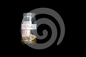 Glass jar labeled travel  on a black background with euro money in it. Euro notes and euro coins.