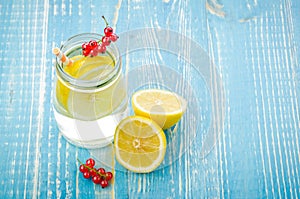 glass jar of lemonade with a lemon and red berries on a blue background/glass jar of lemonade with a lemon and red berries on a b