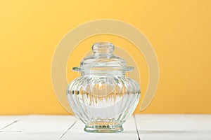 Glass jar with a lid on a white table near the yellow wall