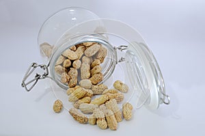 Glass jar with lots of peanuts on a white background