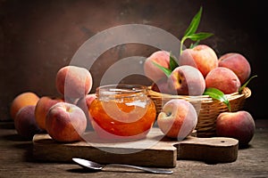 Glass jar of peach jam with fresh fruits