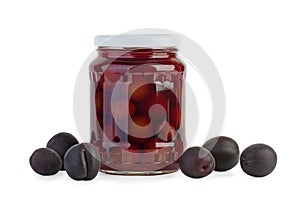 Glass jar with preserved plums and some berries near