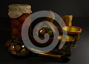 Glass jar of preserved tomato, a spoon with folk painting and a wooden bowl