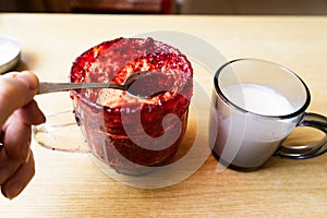 glass jar with raspberry jam. cup of milk or yogurt on wooden table.