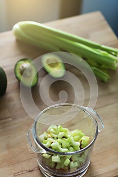 Glass jar with raw chopped celery, avocado and apple, ingridients for health green organic smoothie. Vegan diet and