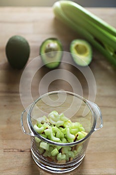 Glass jar with raw chopped celery, avocado and apple, ingridients for health green organic smoothie. Vegan diet and