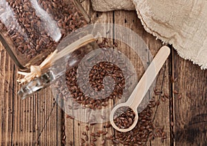 Glass jar of raw natural organic linseed flax-seed with spoon and linen cloth on wooden background