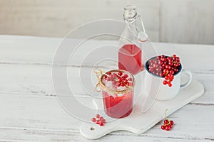 Glass jar of red currant soda drink on a white wooden table. Summer healthy detox lemonade, cocktail or another drink background.