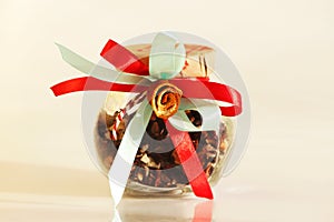 glass jar with red tea Insolent Fruit and colorful tapes with dried orange blossom in the form of a flower on white background.