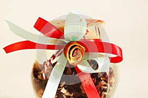 glass jar with red tea Insolent Fruit and colorful tapes with dried orange blossom in the form of a flower on white background.