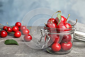 Glass jar with ripe sweet cherries on grey table