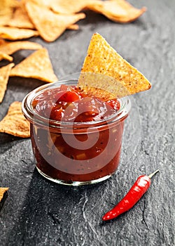 Glass jar of spicy salsa with nachos