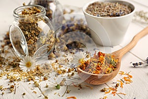 Glass jar and spoon with dried flowers on white wooden table